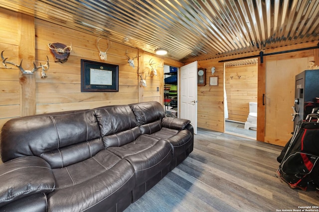 living room featuring a barn door, hardwood / wood-style flooring, and wooden walls