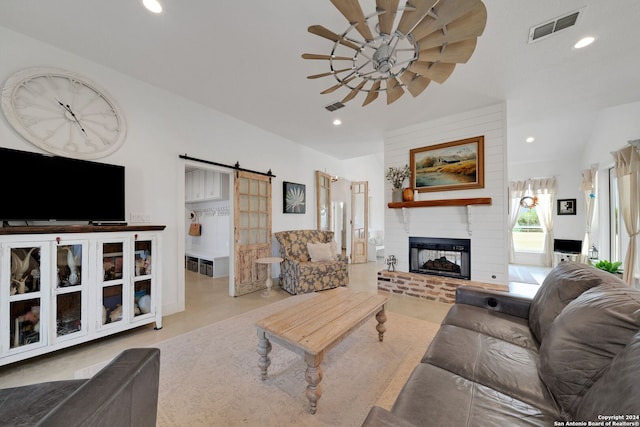 living room featuring ceiling fan, a fireplace, and a barn door