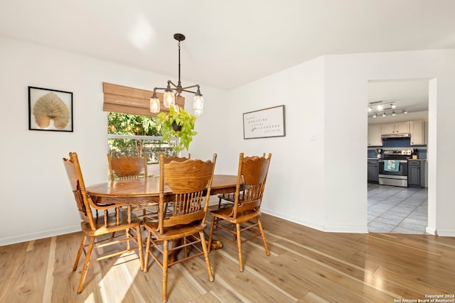 dining space with a chandelier, rail lighting, and light hardwood / wood-style floors