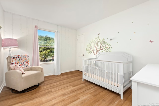 bedroom featuring wood-type flooring and a crib