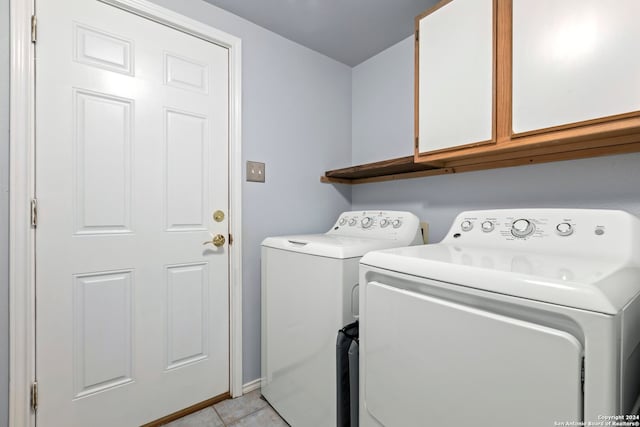 clothes washing area with cabinets, washer and clothes dryer, and light tile patterned floors