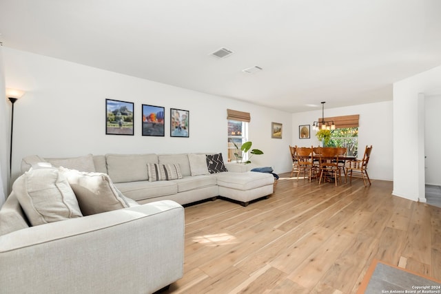 living room with an inviting chandelier and light wood-type flooring