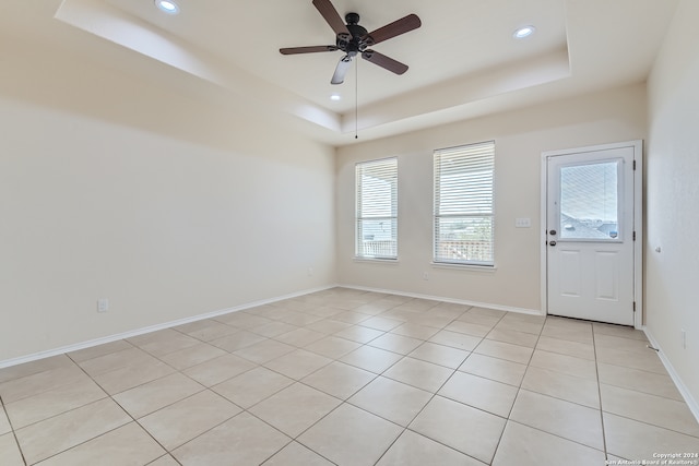 tiled spare room featuring ceiling fan and a raised ceiling