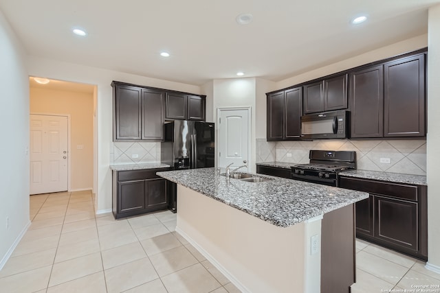 kitchen featuring black appliances, sink, an island with sink, and decorative backsplash