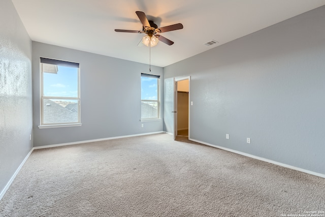 empty room with carpet floors, plenty of natural light, and ceiling fan