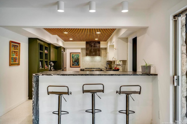 kitchen with white cabinetry, a kitchen breakfast bar, kitchen peninsula, and tasteful backsplash