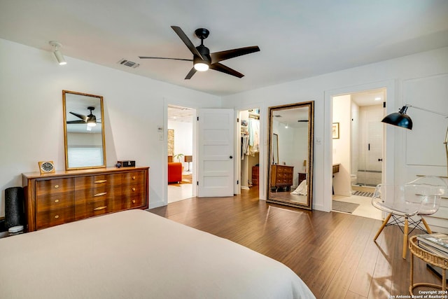 bedroom with ensuite bath, ceiling fan, a walk in closet, a closet, and dark hardwood / wood-style flooring