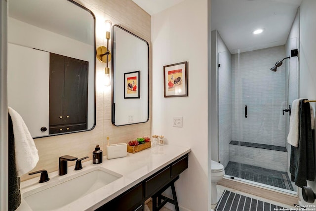 bathroom with hardwood / wood-style floors, a shower with door, vanity, and toilet