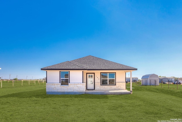 rear view of house featuring a shed and a lawn