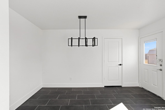 unfurnished dining area featuring a chandelier and dark tile patterned flooring