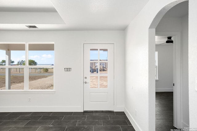 doorway to outside featuring ceiling fan and dark tile patterned floors