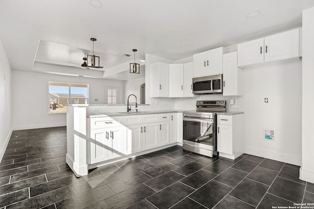 kitchen with appliances with stainless steel finishes, kitchen peninsula, decorative light fixtures, white cabinets, and light stone counters