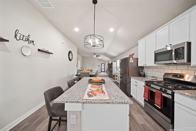 kitchen featuring a kitchen breakfast bar, white cabinets, stainless steel appliances, and vaulted ceiling