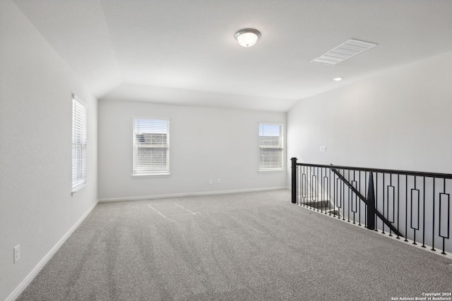 carpeted spare room with lofted ceiling