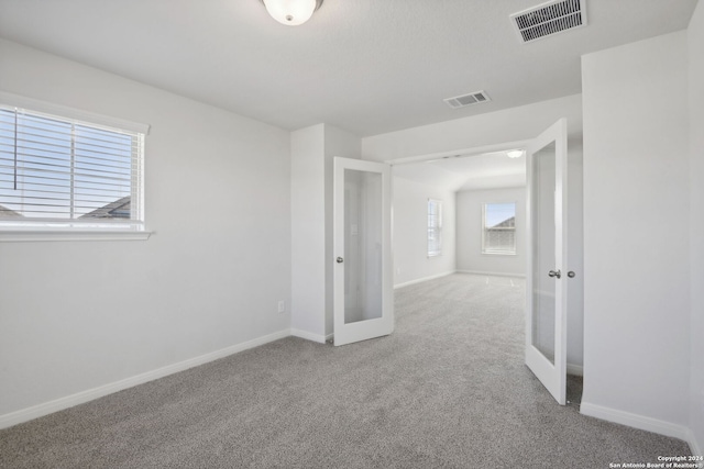 carpeted spare room featuring french doors