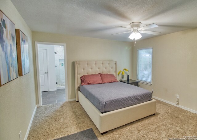 carpeted bedroom with a textured ceiling, ensuite bathroom, and ceiling fan