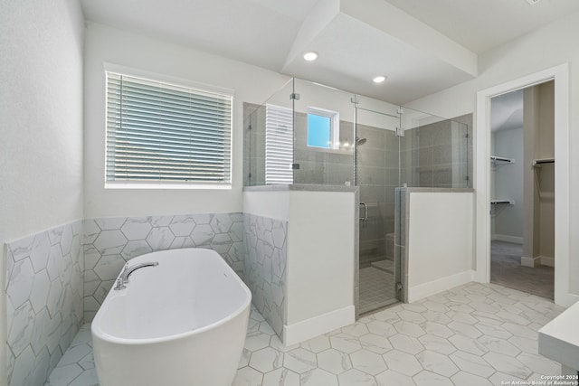 bathroom with tile walls, a healthy amount of sunlight, and separate shower and tub