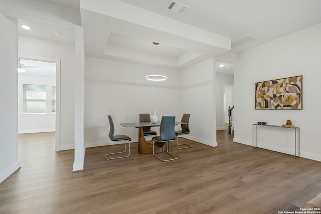 dining room with ceiling fan, wood-type flooring, and a tray ceiling