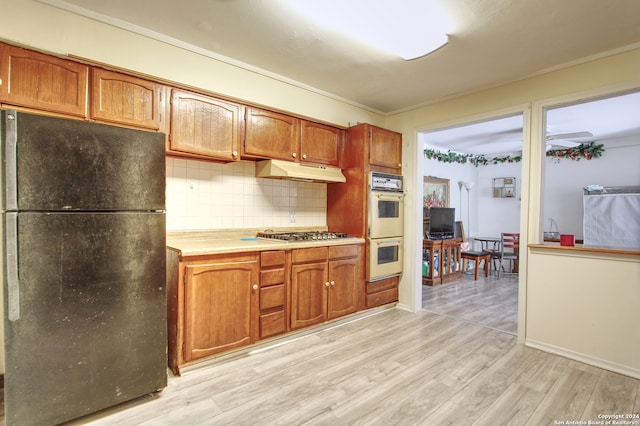 kitchen featuring tasteful backsplash, light wood-type flooring, double oven, black fridge, and ornamental molding