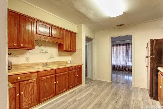 kitchen featuring light hardwood / wood-style flooring, tasteful backsplash, sink, and black refrigerator