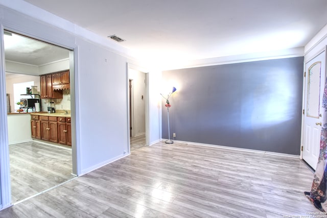 empty room featuring ornamental molding and light hardwood / wood-style flooring