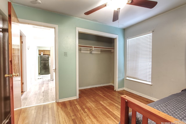 unfurnished bedroom featuring a closet, black fridge, light wood-type flooring, and ceiling fan