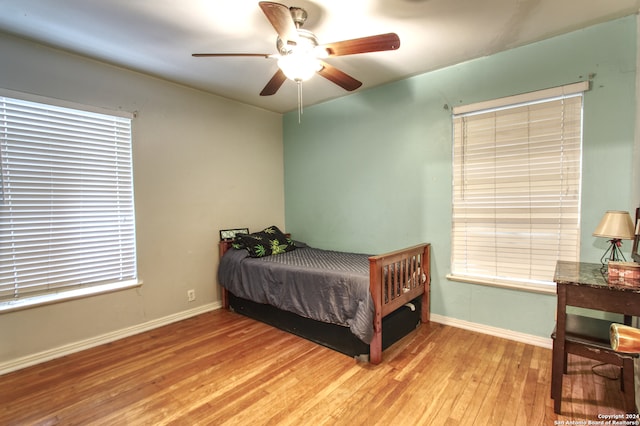 bedroom featuring multiple windows, wood-type flooring, and ceiling fan