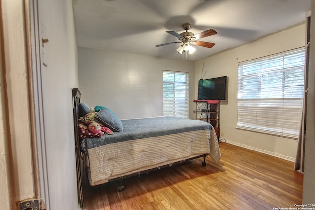 bedroom with ceiling fan, hardwood / wood-style flooring, and multiple windows