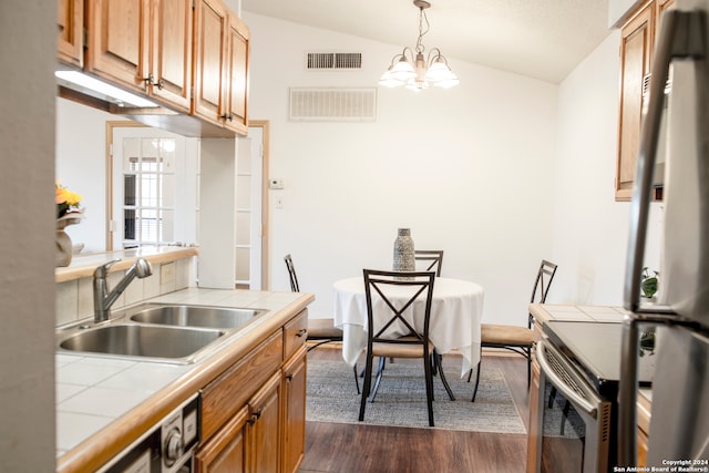 kitchen featuring a notable chandelier, vaulted ceiling, dark wood-type flooring, tile counters, and sink