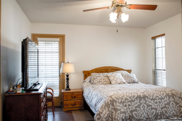 bedroom with ceiling fan, a textured ceiling, and dark hardwood / wood-style floors