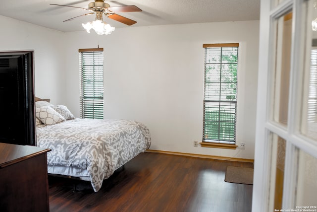 bedroom with a textured ceiling, dark wood-type flooring, and ceiling fan