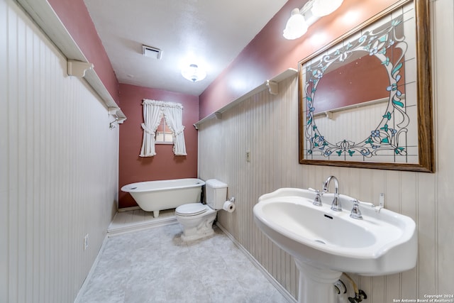 bathroom featuring tile patterned floors, a tub, sink, and toilet