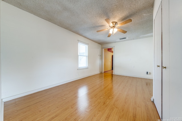 empty room with ceiling fan, a textured ceiling, and light hardwood / wood-style flooring