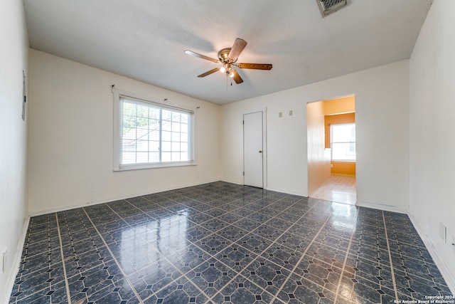 spare room with a textured ceiling, plenty of natural light, and ceiling fan