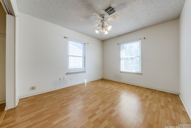 empty room featuring a textured ceiling, light wood-type flooring, and ceiling fan