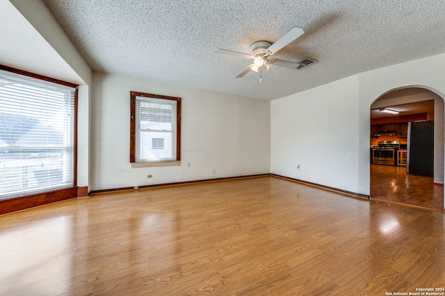 empty room featuring light hardwood / wood-style flooring, a textured ceiling, and ceiling fan