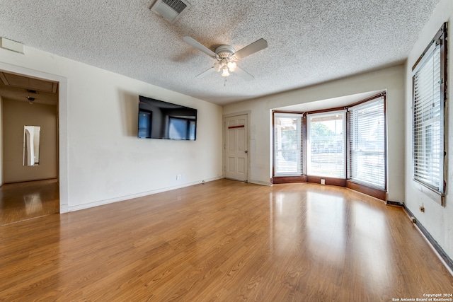 empty room with ceiling fan, a textured ceiling, and light wood-type flooring