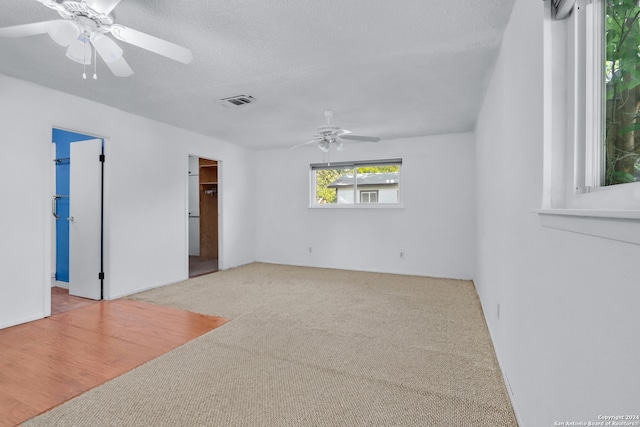 carpeted spare room featuring ceiling fan and a textured ceiling