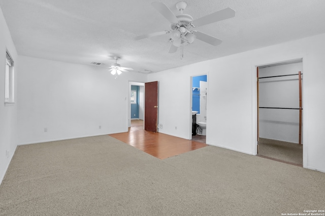 unfurnished bedroom featuring ensuite bathroom, a spacious closet, a closet, ceiling fan, and hardwood / wood-style flooring