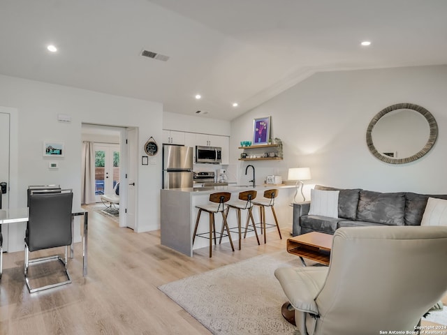 living room with lofted ceiling, french doors, light hardwood / wood-style flooring, and sink