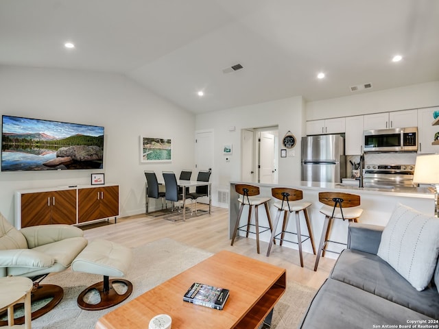 living room featuring lofted ceiling and light hardwood / wood-style floors