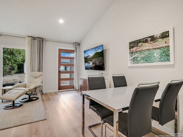 dining space featuring light hardwood / wood-style floors, high vaulted ceiling, and a wealth of natural light