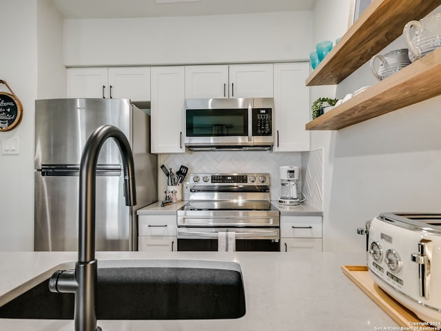 kitchen with white cabinetry, backsplash, and appliances with stainless steel finishes