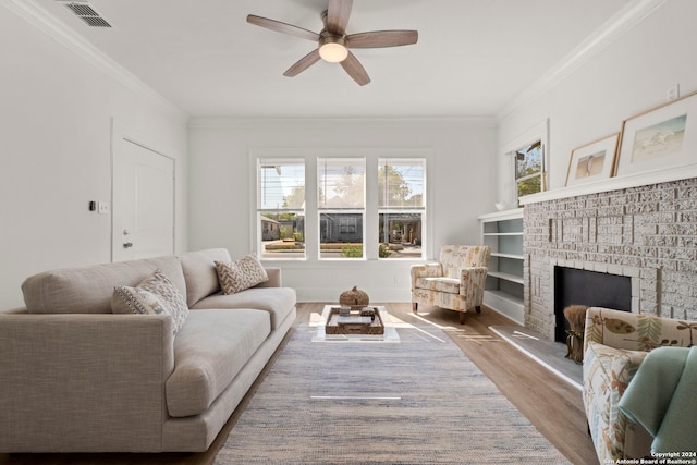 living room featuring crown molding, light hardwood / wood-style flooring, a fireplace, and ceiling fan