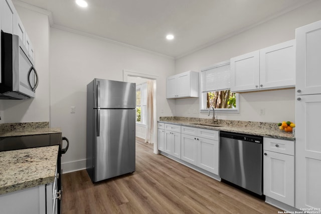 kitchen featuring stainless steel appliances, crown molding, sink, white cabinetry, and light hardwood / wood-style floors