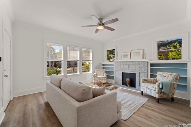 living room featuring ornamental molding, hardwood / wood-style flooring, a fireplace, and ceiling fan