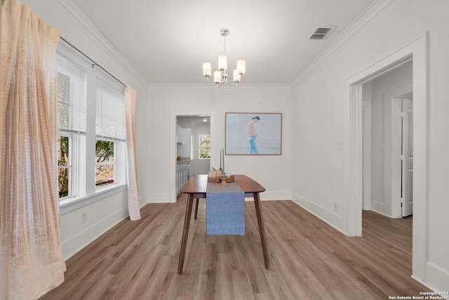 dining space featuring crown molding, a notable chandelier, and light hardwood / wood-style floors