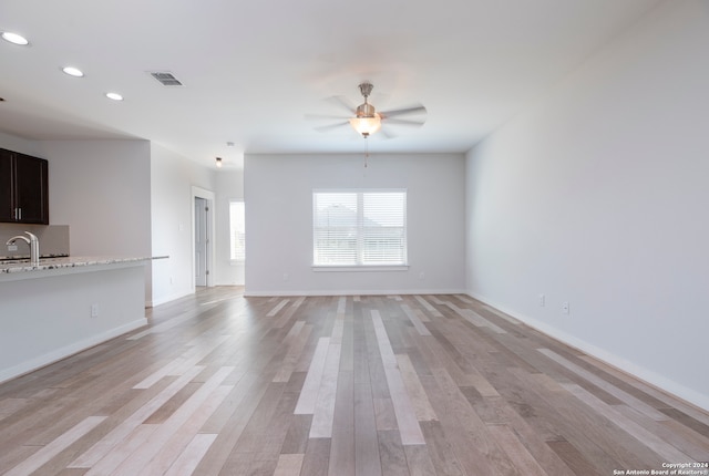 unfurnished living room with light hardwood / wood-style floors, sink, and ceiling fan