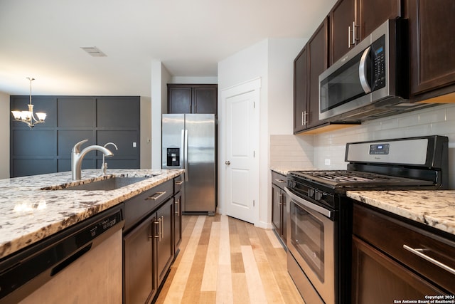 kitchen with sink, dark brown cabinets, stainless steel appliances, and light wood-type flooring