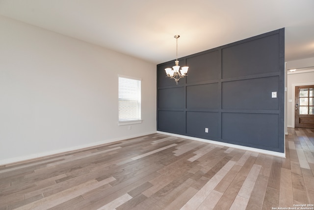 unfurnished dining area featuring an inviting chandelier and light wood-type flooring